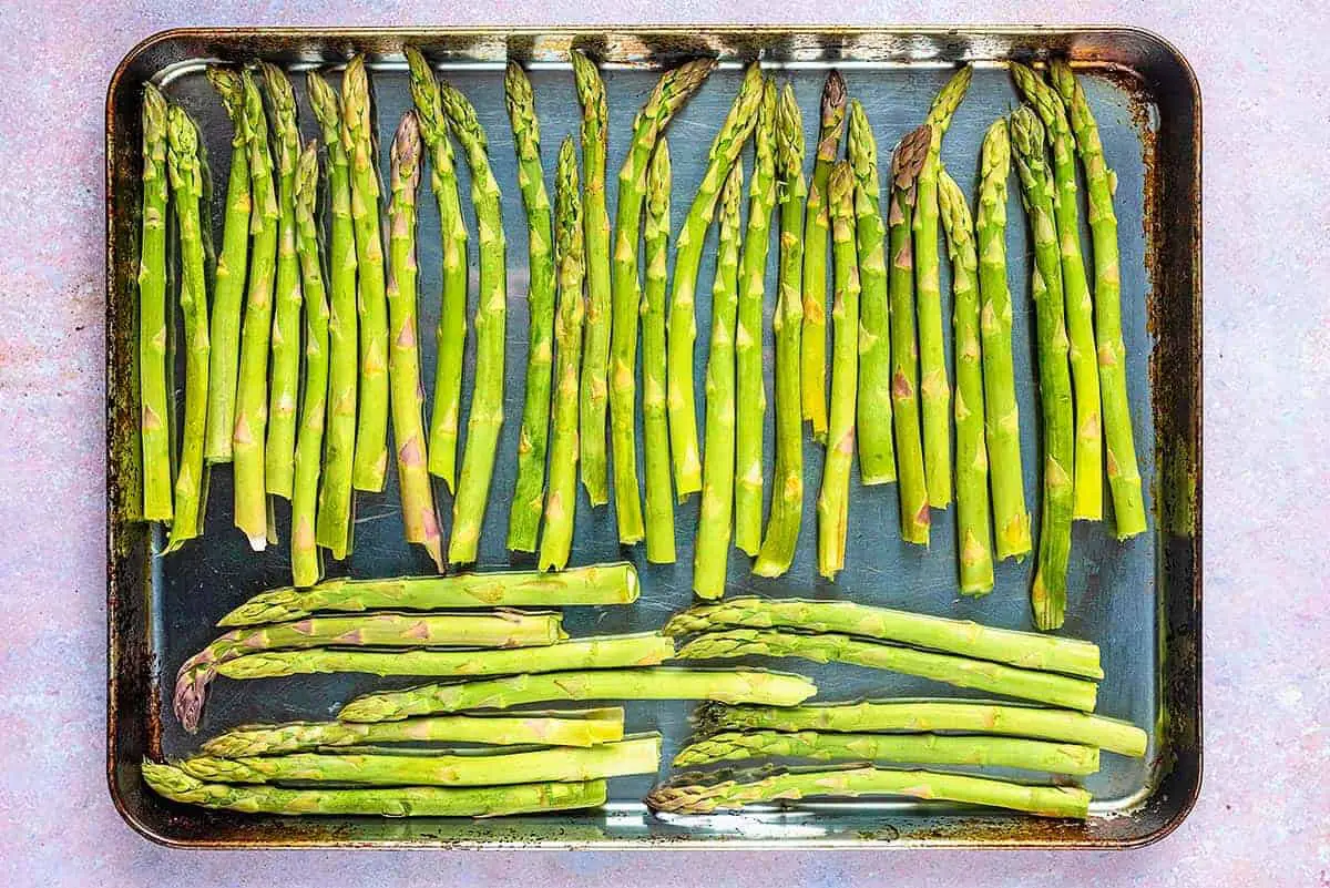 A large stainless steel baking tray covered in asparagus spears.