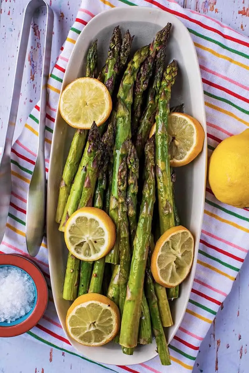 Roasted Lemon Asparagus on a serving dish next to a lemon.