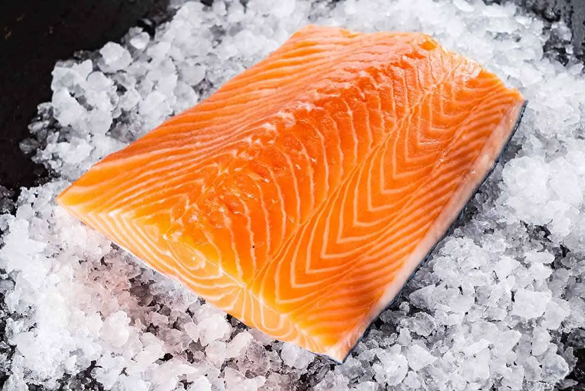 A half side of uncooked salmon sat on crushed ice.