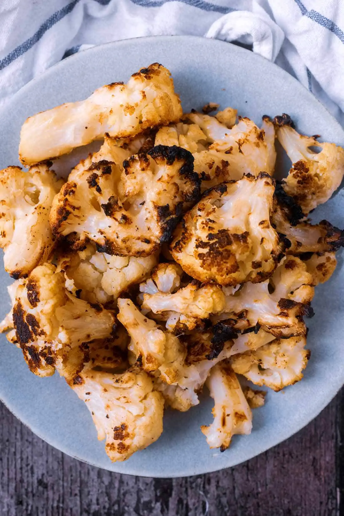 Cooked cauliflower with slightly charred edges on a grey plate.