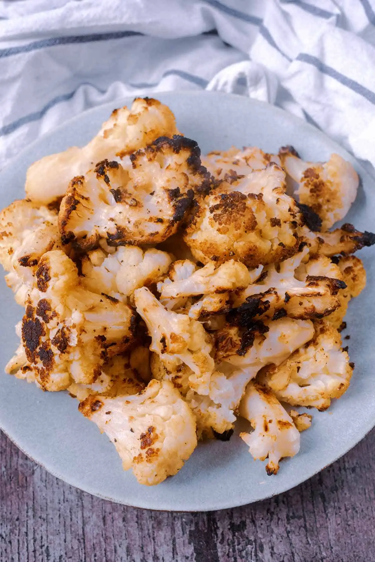 A plate of cooked cauliflower in front of a striped towel.
